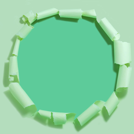 Light green torn paper with hole against green background. Minimal abstract colorful backgroundの写真素材