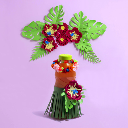Decorating summer drinks for Hawaiian party. Juice in bottle with paper decorations in style of Hawaiian holidays. Exotic flowers and leaves. Paper art and paper craftの写真素材