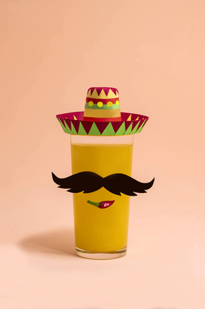 Cocktail in glass with decor for Cinco de Mayo. Paper sombrero and mustache, hot peppers for decorating drink in glass. Cinco de Mayo is federal holiday in Mexico on May 5th. Minimal holiday conceptの写真素材