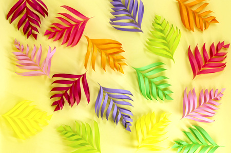 Multicolored volumetric leaves of paper on yellow background. Paper art and craft. Trendy hobby. Minimal decorative conceptの写真素材