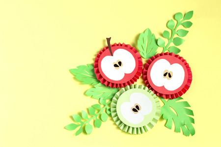 Colorful paper apple slices and leaves on yellow background. Paper art and craft. Trendy hobby. Creative, vegan, healthy or food art conceptの写真素材