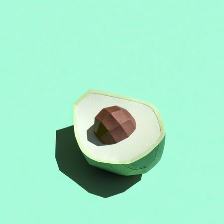 Paper half avocado with seed casts shadow in bright sunshine. Paper art and craft. Trendy hobby....