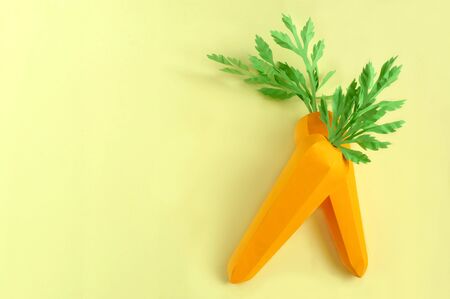 Two paper carrots on yellow background. Paper art and craft. Trendy hobby. Creative, vegetarian, healthy or food art conceptの写真素材