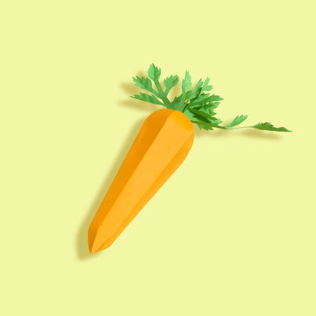 Paper carrot on yellow background. Paper art and craft. Trendy hobby. Creative, vegetarian, healthy or food art conceptの写真素材