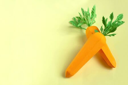 Two paper carrots on yellow background. Paper art and craft. Trendy hobby. Creative, vegetarian, healthy or food art conceptの写真素材