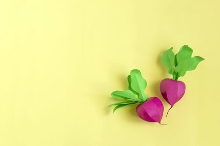 Colorful volumetric radishes made from paper on yellow background. Paper art and craft. Trendy hobby. Creative, vegetarian, healthy or food art conceptの写真素材