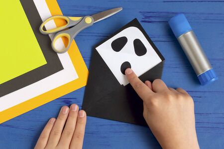 How to make original envelopes for Halloween greetings. Children's art project. DIY concept. Step-by-step photo instruction. Step 6. Glue eyes and mouth of ghostの写真素材