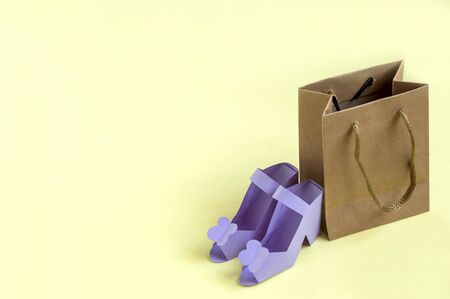 Paper shoes and bag on yellow background. Paper art and craft. Trendy hobby. Seasonal sale concept. Shoes for sale. Minimal style, copy spaceの写真素材