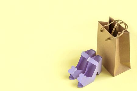Paper shoes and bag on yellow background. Paper art and craft. Trendy hobby. Seasonal sale concept. Shoes for sale. Minimal style, copy spaceの写真素材