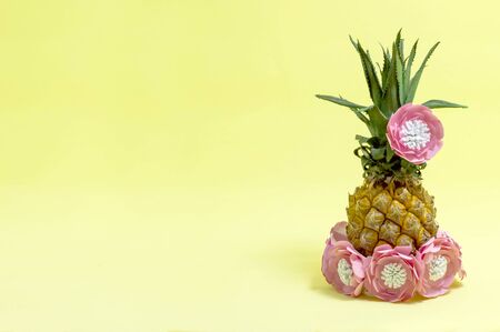 Pineapple decorated with paper flowers in style of Hawaiian party. Art concept of summer holidays and vacations. Bright color, summer accessories. Minimal styleの写真素材