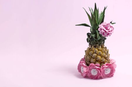 Pineapple decorated with paper flowers in style of Hawaiian party. Art concept of summer holidays and vacations. Bright color, summer accessories. Minimal styleの写真素材