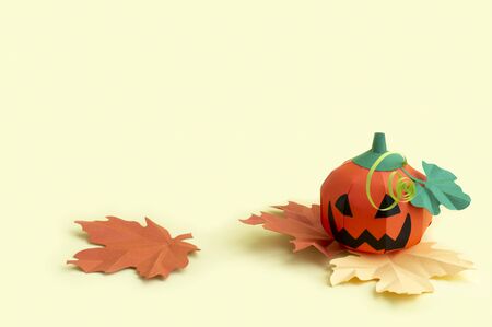 Volumetric paper Jack-o-lantern with autumn leaves on yellow background. Paper art and craft. Festive Halloween concept. Copy spaceの写真素材
