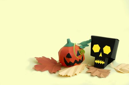 Volumetric paper skull and Jack-o-lantern with autumn leaves on yellow background. Paper art and craft. Festive Halloween concept. Copy spaceの写真素材