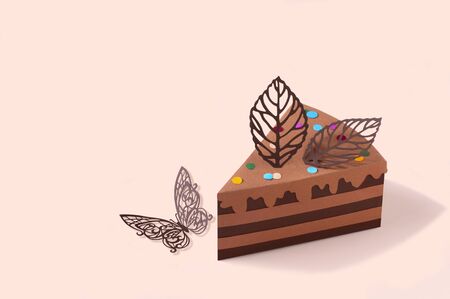 Piece of paper chocolate cake and butterfly. Cake is decorated with paper chocolate leaves. Volumetric handmade paper objects. Paper art and craft. Trendy hobby. Minimal art food concept. Copy spaceの写真素材