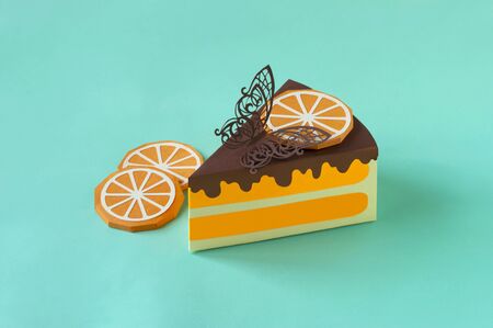 Piece of paper orange cake. Cake is decorated with slice of paper orange and chocolate butterfly....