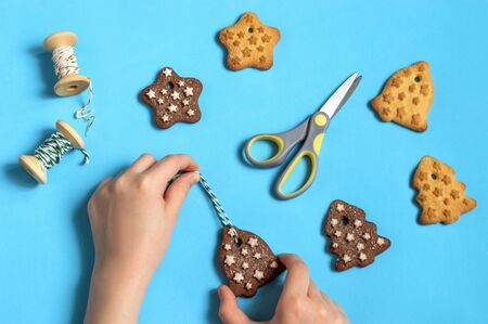 Female hand holds cookies to decorate Christmas tree. Delicious homemade Christmas cookies in shape of bells, Christmas trees and stars. Festive christmas conceptの写真素材
