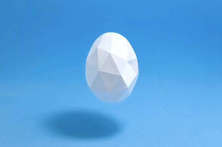 Paper polygonal egg levitates on blue background. Paper art and craft. Volumetric handmade paper objects. Minimal easter conceptの写真素材