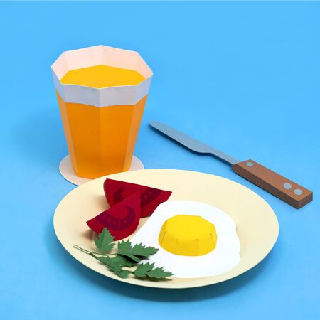 Paper fried eggs, sliced tomato on plate and orange juice in glass. Paper art and craft. Real volumetric handmade paper objects. Minimal artistic food conceptの写真素材
