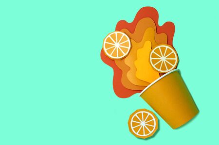 Paper cup with spilled orange juice. Bursts of juice spread in layers with orange slices. Paper craft and paper art. Real volumetric handmade paper objects. Minimal art food concept. Copy spaceの写真素材