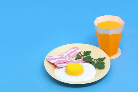 Paper fried eggs, bacon strips on plate and orange juice in glass. Paper art and craft. Real volumetric handmade paper objects. Minimal artistic food conceptの写真素材