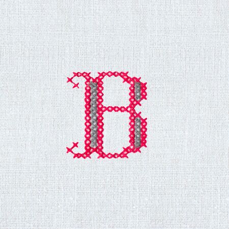 Vintage cross-stitch letter B on linen homespun fabric. Embroidered letter B close-up. Handmade artの写真素材