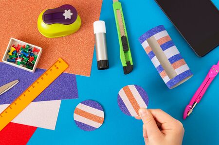 Child makes stand for smartphone from toilet paper sleeve. Children's craft during quarantine. How to captivate children at home during coronavirus pandemic. Step-by-step photos. Step 10の写真素材