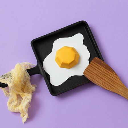 Cast-iron frying pan with paper fried eggs and wooden spatula. Realistic handmade paper objects. Paper art and craft. Minimal art food concept. Square imageの写真素材