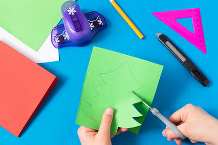 Child makes card with Christmas tree. Original children's art project. DIY concept. Step-by-step photo instructions. Step 4. Cut Christmas treeの写真素材