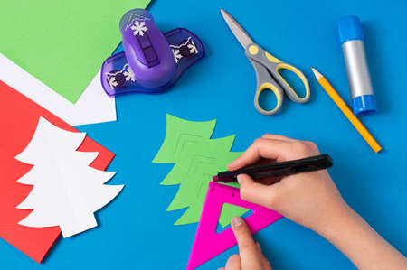 Child makes card with Christmas tree. Original children's art project. DIY concept. Step-by-step photo instructions. Step 6. Make cuts along linesの写真素材