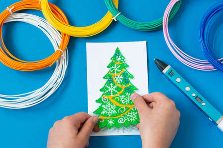 Child makes toys for Christmas tree with 3D pen. Original art project for children. New technology. DIY concept. Step by step photo instruction. Step 3. Detach Christmas tree from templateの写真素材