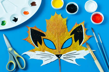 Mask painted on maple leaf. Drawing on autumn leaves. Fox mask for autumn carnival or party. Art project for children. DIY conceptの写真素材