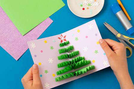 How to make Christmas card with volumetric tree. Original project for children. DIY concept. Step-by-step photo instructions. Step 9. Decorate card with confetti and snowflakesの写真素材
