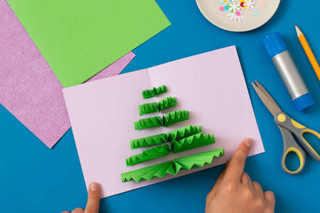 How to make Christmas card with volumetric tree. Original project for children. DIY concept. Step-by-step photo instructions. Step 8. Glue stripes on other half of cardの写真素材