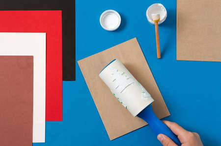 Child decorates craft gift bags for Christmas. Original project for children. DIY concept. Step-by-step photo instructions. Step 3. Make pattern with sticky roller with glued Christmas treesの写真素材