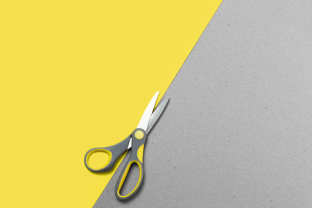 Two-tone paper background with scissors in trending color combinations of 2021. Trend colors of 2021 are yellow and gray. Copy spaceの写真素材