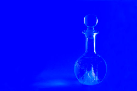 Glass carafe with glowing magical landscape inside on blue background. Egg protein in water forms beautiful patterns. Mystery, magic ritual. Fortune-telling on egg. Minimal art conceptの写真素材