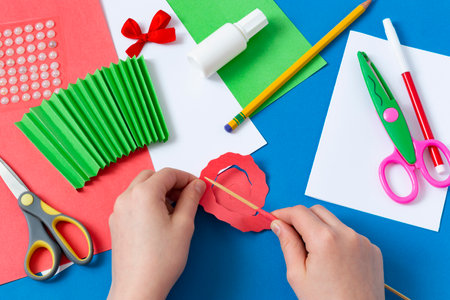 Child makes greeting card for Mother's Day. Art project for children. DIY concept. Step-by-step photo instruction. Step 6. Twist spiral onto skewerの写真素材