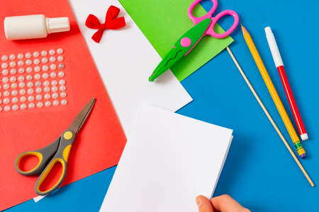 Child makes greeting card for Mother's Day. Art project for children. DIY concept. Step-by-step photo instruction. Step 2. Fold sheet in half for base of postcardの写真素材