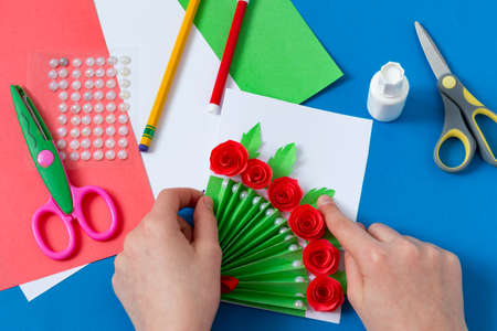 Child makes greeting card for Mother's Day. Art project for children. DIY concept. Step-by-step photo instruction. Step 15. Glue leavesの写真素材