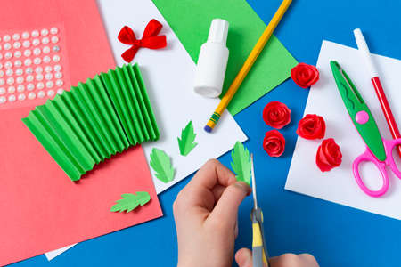 Child makes greeting card for Mother's Day. Art project for children. DIY concept. Step-by-step photo instruction. Step 9. Cut leavesの写真素材
