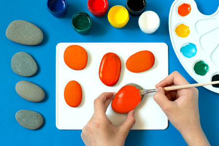 Lettering on sea stones for Halloween design. Children's art project. DIY concept. Decor for holiday party. Step 2. Base paint applicationの写真素材