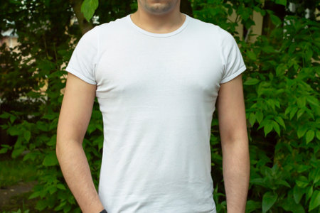 White cotton T-shirt mockup. Young man in white T-shirt on background of green foliage. T-shirt mockup for design promotionの写真素材