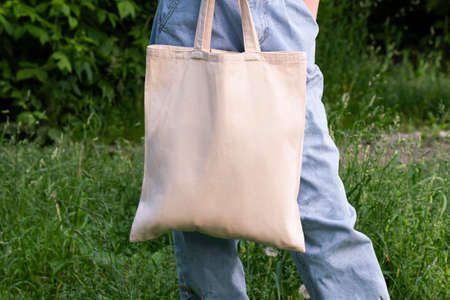 Empty reusable canvas tote bag mockup. Natural canvas eco-friendly shopper bag in girl's hand. Mockup for presentation of design or brandの写真素材