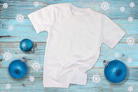 T-shirt mockup on light blue wooden background with Christmas balls and snowflakes. White cotton t-shirt mockup for design promotionの写真素材