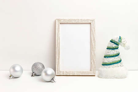 Photo frame mockup with Christmas decorations, silver Christmas balls and Santa hat on white backgroundの写真素材
