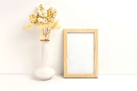 Mockup photo frame and vase with dried flowers. Empty photo frame mockup to showcase your art and photo projectsの写真素材