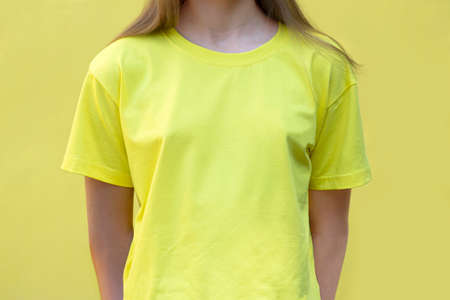 Mockup of yellow cotton T-shirt. Teenage girl in yellow T-shirt on yellow background. T-shirt mockup for design promotionの写真素材