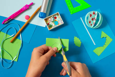 Making Christmas card with volumetric Christmas ball. Original project for children. DIY concept. Step-by-step photo instructions. Step 10. Cut holly leavesの写真素材