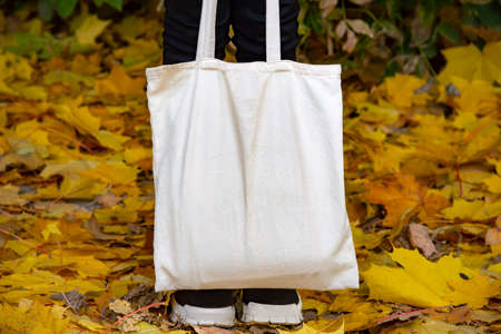 Empty reusable canvas tote bag mockup. Natural canvas eco-friendly shopper bag in girl's hand. Mockup for presentation of design or brandの写真素材