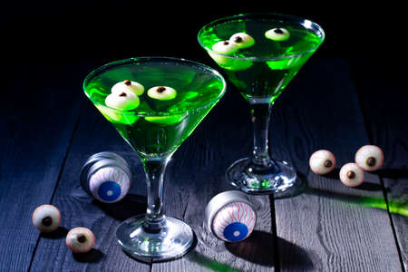 Glasses with Halloween green cocktails and eyeballs. Scary drinks with decorations for Halloween partyの写真素材